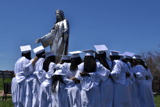 Graduates standing in front of statue