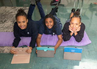 Students working on tablet computers, laying on pillows